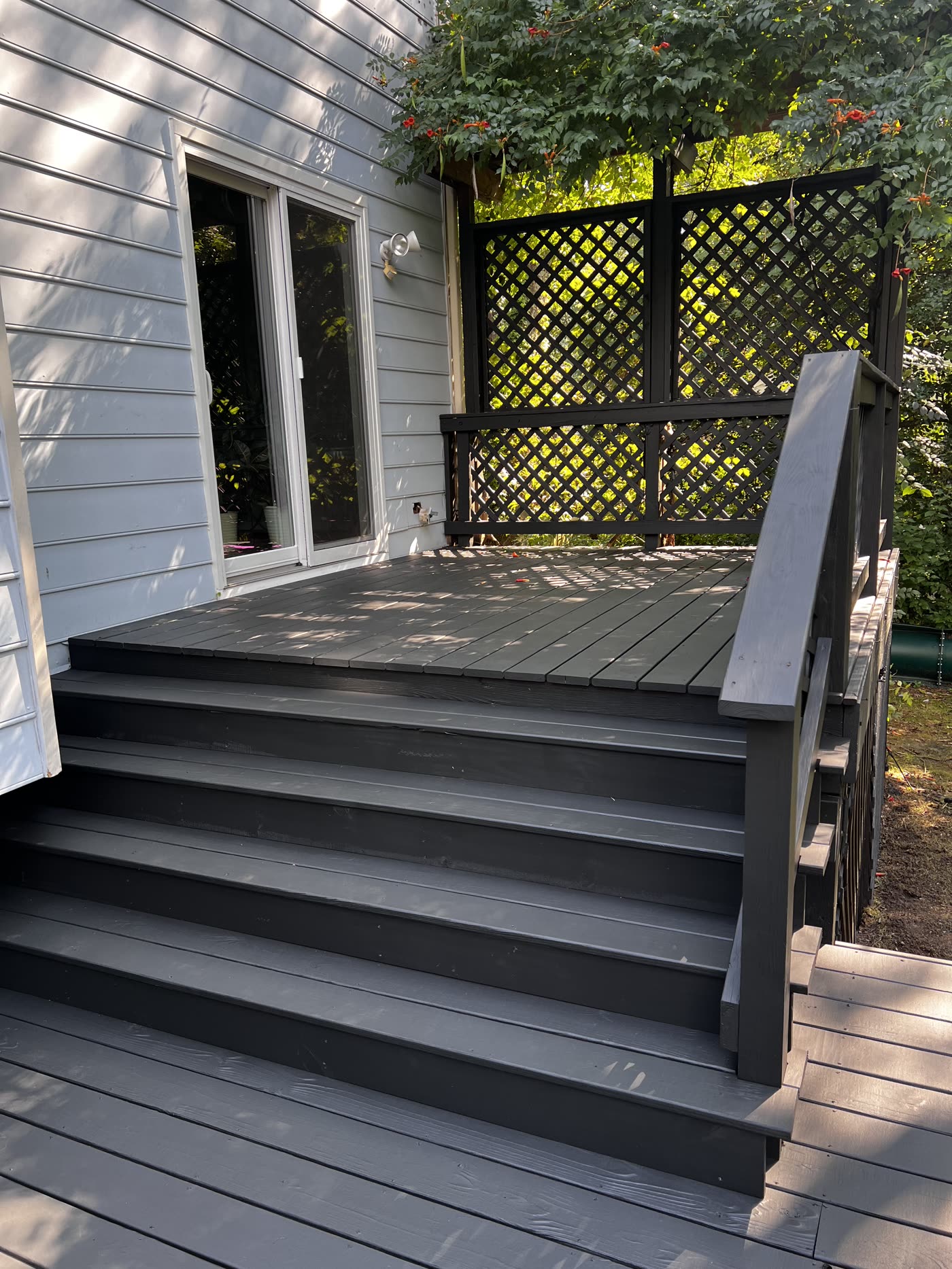 Refinished deck stairs and black railing with lattice panels